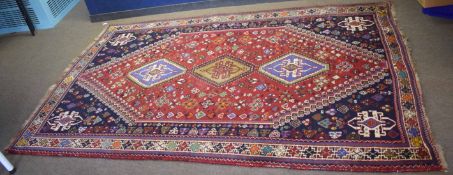 Caucasian style wool carpet, central panel of three lozenges, red and blue field with multi-coloured