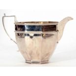 George V milk jug of faceted circular form with applied handle and spout, width 12.8cm, weight