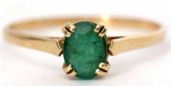 Yellow metal emerald ring, the oval faceted emerald 8x6mm, four claw set and raised between plain