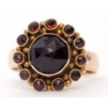Garnet cluster ring featuring a large central garnet of rose cut, 8.7mm diam, within a surround of