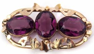 Victorian three-stone brooch, the ornate metal scroll mount featuring three bezel set oval faceted