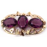 Victorian three-stone brooch, the ornate metal scroll mount featuring three bezel set oval faceted