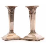 Two George V candlesticks with integral square section sconces and columns on spreading square bases