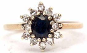 Modern 9ct gold, sapphire and diamond cluster ring, the oval faceted shaped sapphire raised within a