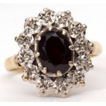 18ct gold garnet and diamond cluster ring, the oval shaped faceted garnet claw set and raised within