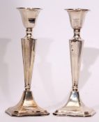 Two George V single candlesticks, each with fixed and faceted square sconces on tapering columns and