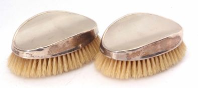 Two George VI silver backed hairbrushes, each of shaped oval form with engine turned decorated