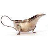 George VI gravy boat of typical form with cast and applied rim, strapwork handle and raised on three