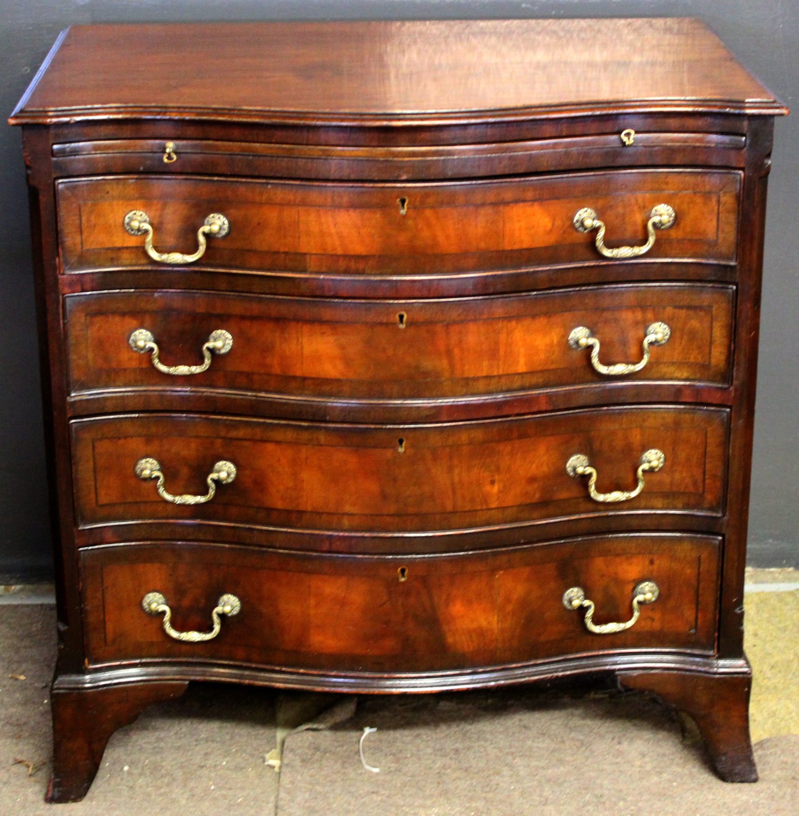 Reproduction mahogany serpentine front bachelor's chest with brushing slide over four drawers with