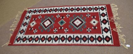 Good quality modern floor rug predominantly in red and cream with black repeating border of