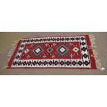 Good quality modern floor rug predominantly in red and cream with black repeating border of