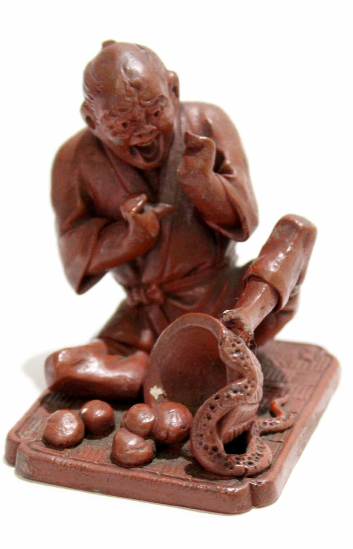 Oriental stained plaster figure of a man on a rectangular base, alarmed by a snake, 7cm high