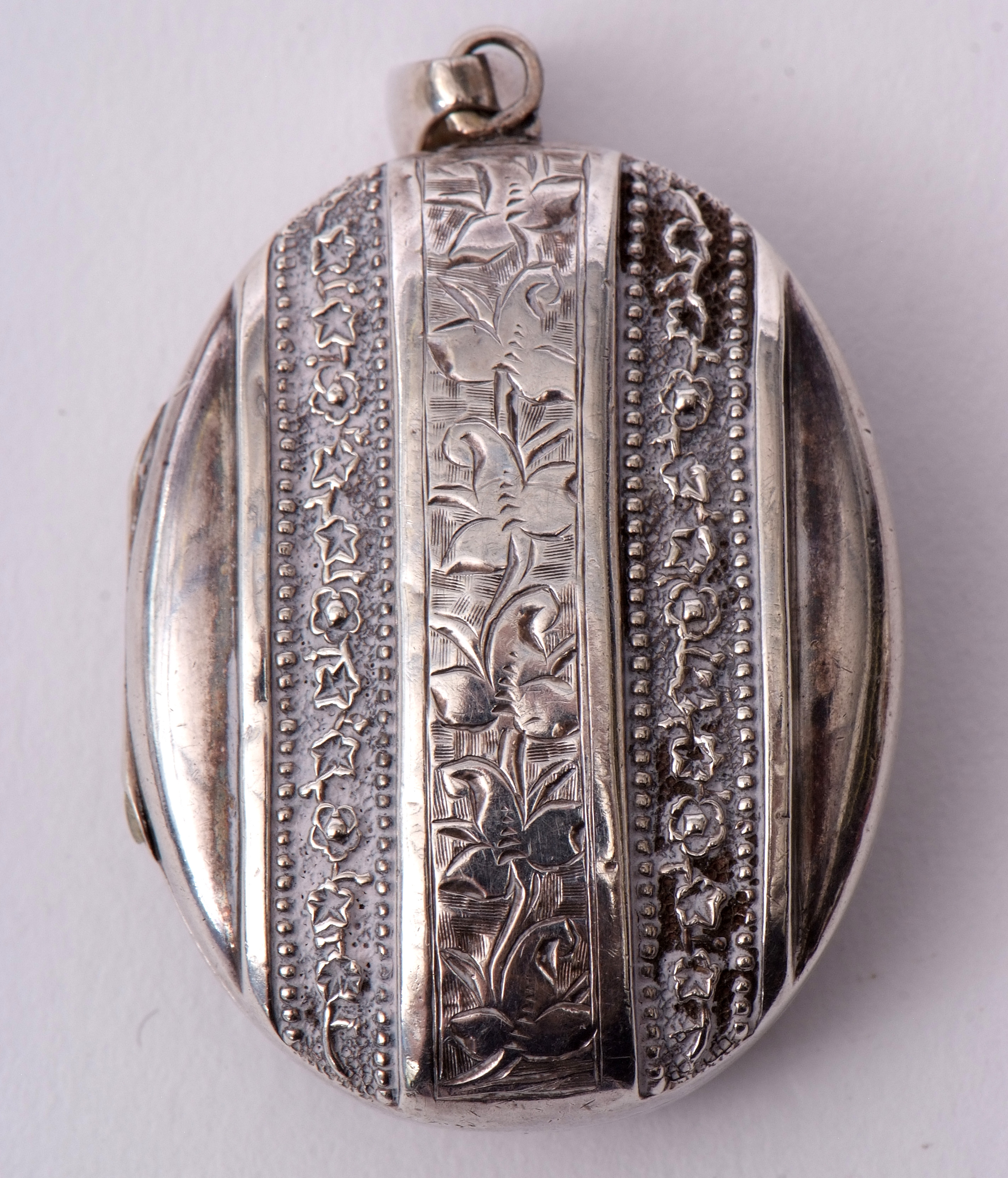 Antique oval plated locket of ribbon design, chased and engraved detail, 4.5 x 3.5cm