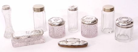 Mixed Lot: comprising four various silver lidded cylindrical toiletry jars, all with embossed