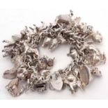 Hallmarked silver curb link chain suspending a large quantity of white metal charms, mainly animals,