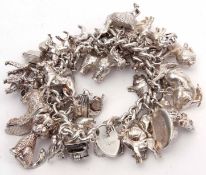 Hallmarked silver curb link chain suspending a large quantity of white metal charms, mainly animals,