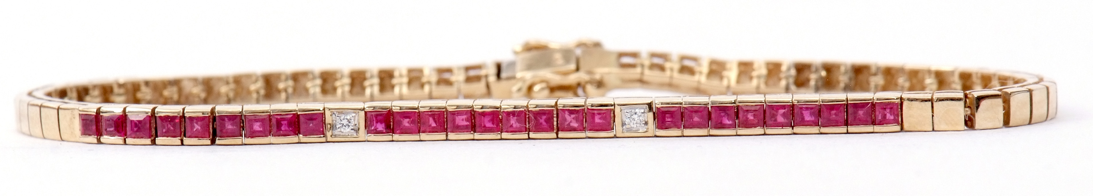 A 14K stamped ruby and diamond line bracelet, featuring 24 channel set calibre cut rubies and two