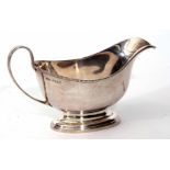 George VI gravy boat of polished form with beaded rim, strap work handle on spreading oval base,