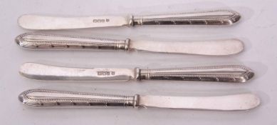 Four George V dessert knives with plain polished blades and hard soldered cast and applied