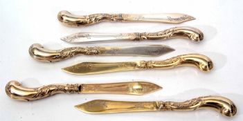 Six German silver gilt dessert knvies each with stylised foliate pistol grip handles and engraved