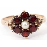 A 9ct gold, garnet and pearl cluster ring featuring a central split cultured pearl raised within a