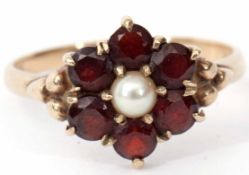 A 9ct gold, garnet and pearl cluster ring featuring a central split cultured pearl raised within a