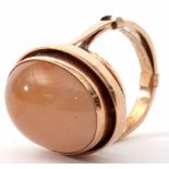 A contemporary quartz and yellow metal ring centring an oval cabochon in a plain polished mount,