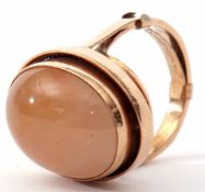 A contemporary quartz and yellow metal ring centring an oval cabochon in a plain polished mount,