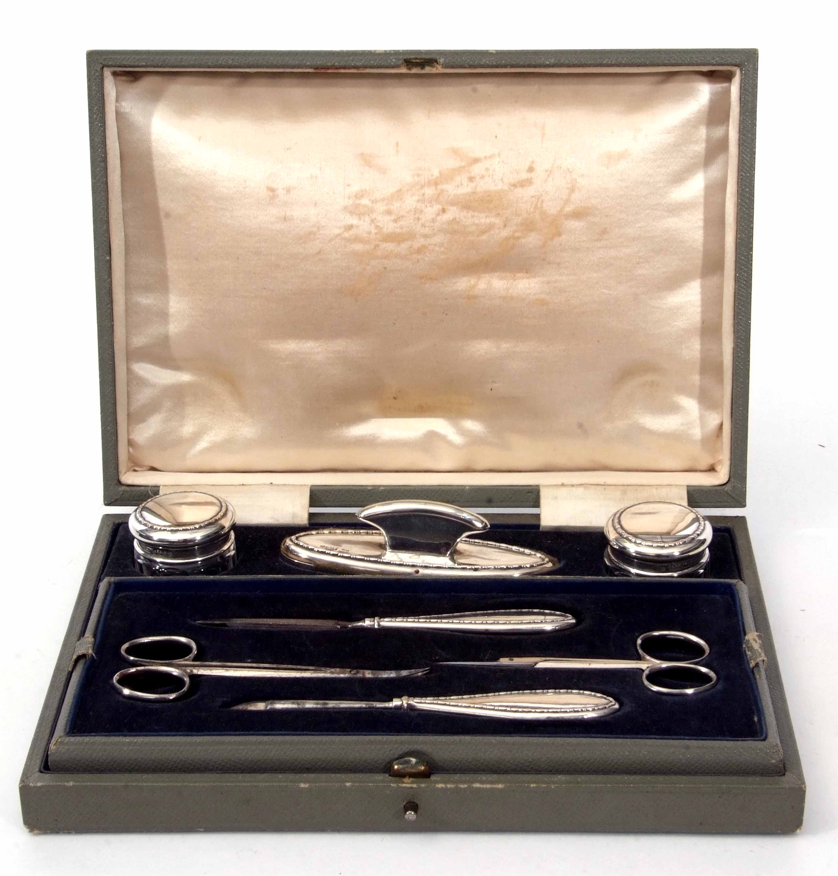 George V cased dressing table set comprising two silver lidded and faceted clear glass rouge pots