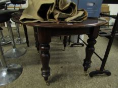 VICTORIAN CIRCULAR EXTENDING DINING TABLE ON TURNED LEGS RAISED ON BRASS CASTERS (WITH ONE LEAF)