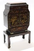 Oriental small cabinet decorated in a chinoiserie aesthetic style, seated on plain wooden stand,