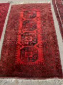 Shiraz carpet, central panel of four lozenges, three gull border and red field, 182 x 106cm