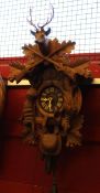 Bavarian style wall clock, the clock surrounded by carved wooden game with crossed swords and a