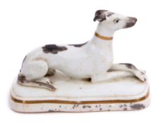 Mid-19th century English porcelain model of a greyhound with black markings seated on a shaped white