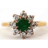 18ct gold emerald and diamond cluster ring, the circular shaped emerald multi-clawed set within a