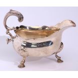 George II large sauce boat with card cut rim, leaf clad flying scroll handle and supported on