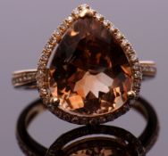 Modern champagne topaz and diamond ring, the pear cut champagne topaz approx 7.43ct, set within a