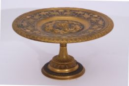 Gilt metal Arts & Crafts style tazza, the centre decorated with Bacchanalian putti and the border