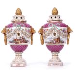 Pair of Continental porcelain urns with lion mask handles and reticulated covers, both decorated