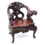 Oriental hardwood throne type tub chair, arched back and two arms terminating in griffons over a
