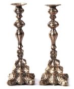 Pair of Continental rococo style white metal candlesticks on shaped square bases with knopped