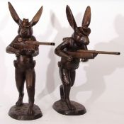 Pair of modern bronze patinated cast metal studies of "cowboy or hunter" rabbits, each clutching