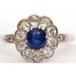Precious metal sapphire and diamond cluster ring, the oval faceted sapphire raised in a surround