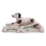 Early 19th century English porcelain model of a dog seated on a raised rococo base, finely painted