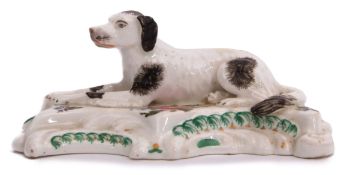 Early 19th century English porcelain model of a dog seated on a raised rococo base, finely painted