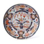 Large 19th century Japanese Imari charger, the centre decorated with a vase of flowers in iron red