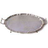 George V shaped oval tea tray with pie-crust edge and two side handles, plain centre, raised on four