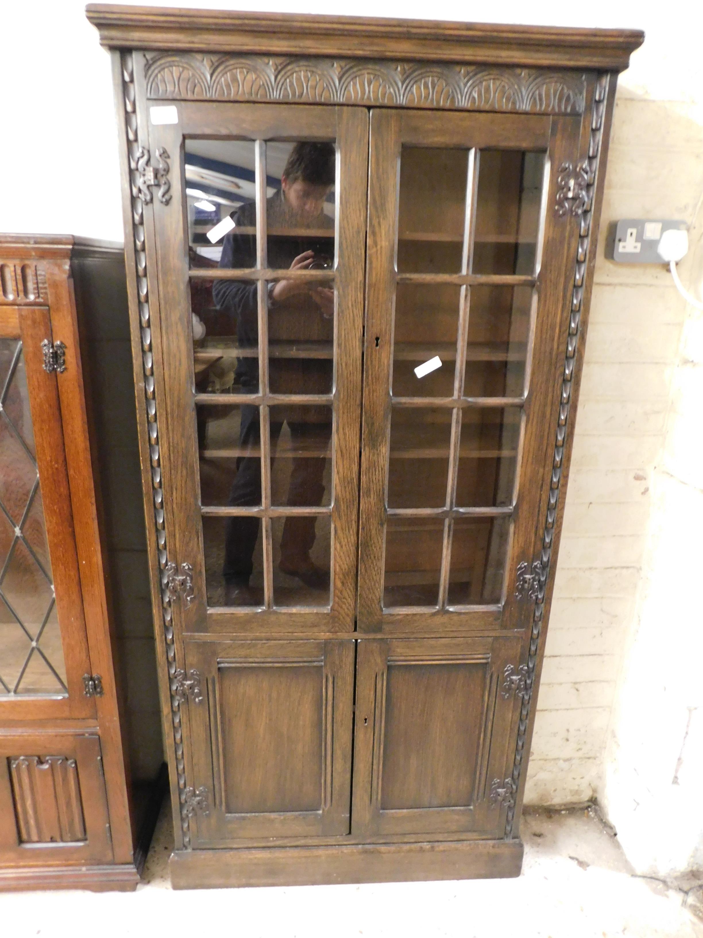 MID-20TH CENTURY OAK FRAMED CABINET WITH GLAZED DOOR OVER PANELLED DOOR WITH CARVED DETAIL