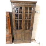 MID-20TH CENTURY OAK FRAMED CABINET WITH GLAZED DOOR OVER PANELLED DOOR WITH CARVED DETAIL