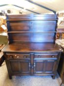 DARK STAINED OAK SIDEBOARD OR DRESSING WITH TWO FIXED SHELVES AND PANELLED BACK, THE BASE WITH TWO